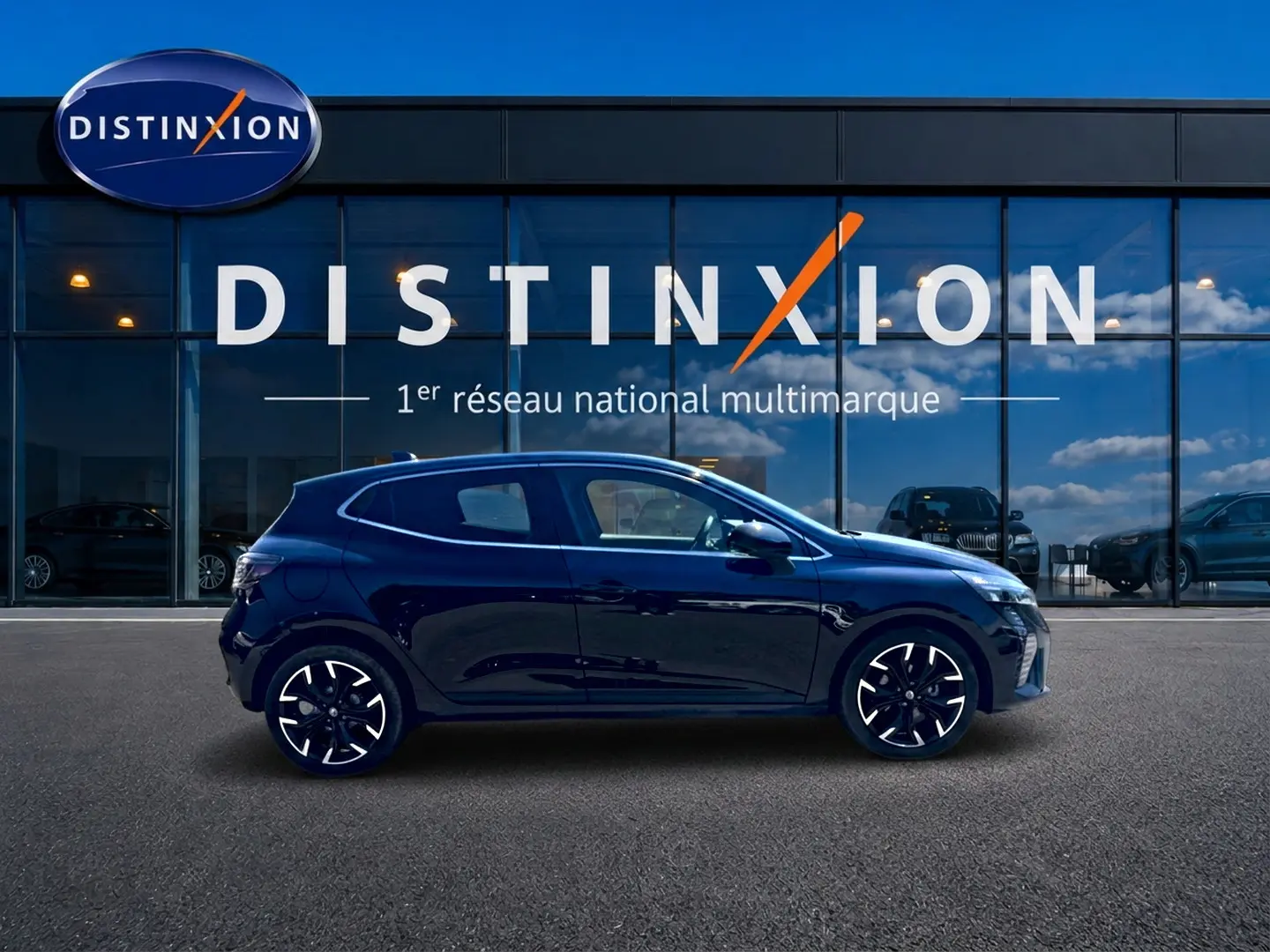 Profil droit d'une Renault Clio V noire 2025, avec jantes alliage et lignes épurées, devant une vitrine Distinxion.