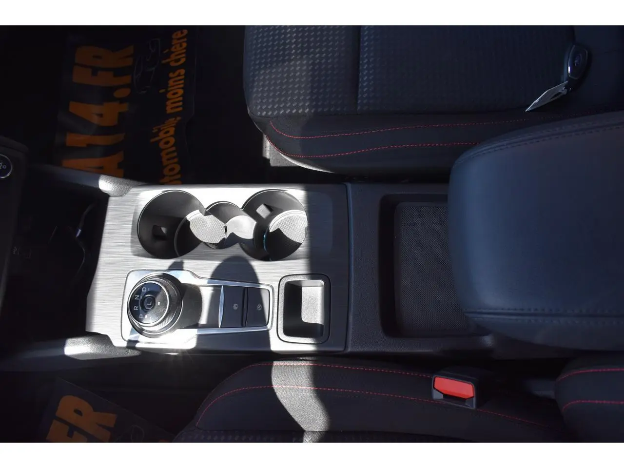 Vue plongeante sur la console centrale de la Ford Focus SW 2025 noire, avec sélecteur rotatif de boîte auto et porte-gobelets.