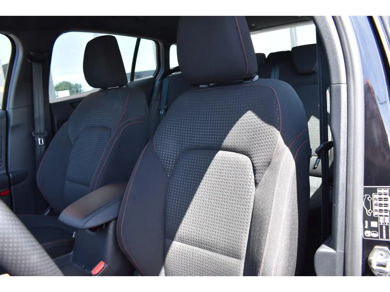 Vue intérieure rapprochée des sièges avant noirs avec surpiqûres rouges d’une Ford Focus SW 2025 Agate Black Metallic.