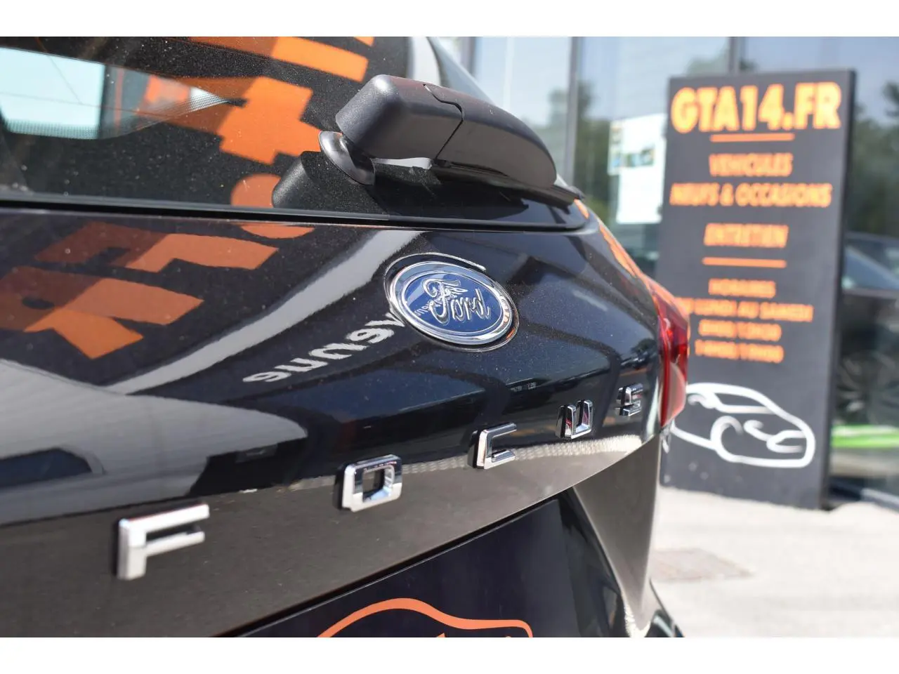 Gros plan sur l'arrière en Agate Black Metallic d'une Ford Focus SW avec logo et lettrage distinctifs visibles.