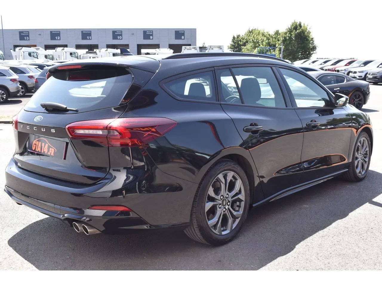 Vue 3/4 arrière droite de la Ford Focus SW 1.5 EcoBlue noire métallisée avec double sortie d'échappement et jantes alliage.