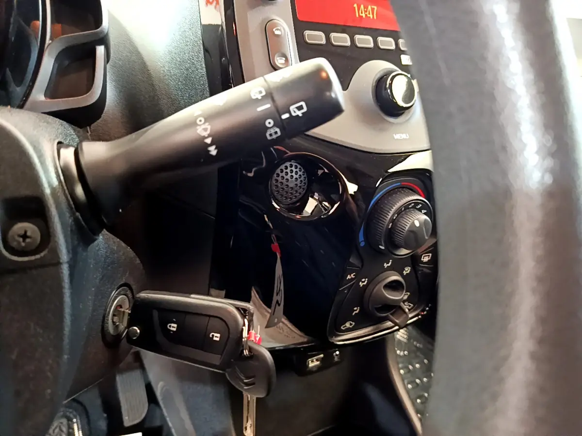 Gros plan sur la console centrale et la clé insérée côté gauche d'une Citroën C1 blanche, avec commandes climatisation visibles.