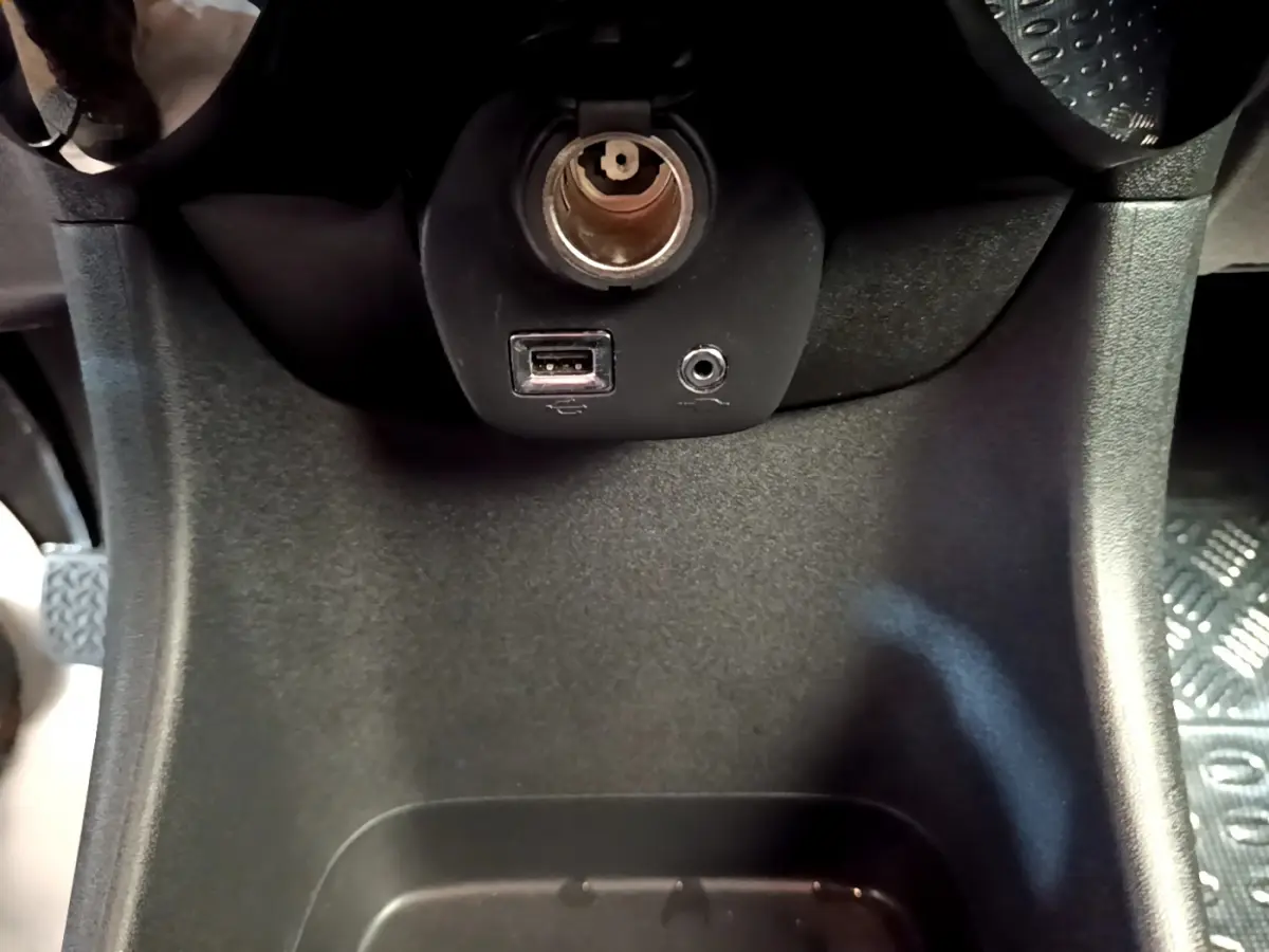 Prise USB et prise jack sur la console centrale noire de la Citroën C1 blanche, vue en gros plan intérieur.