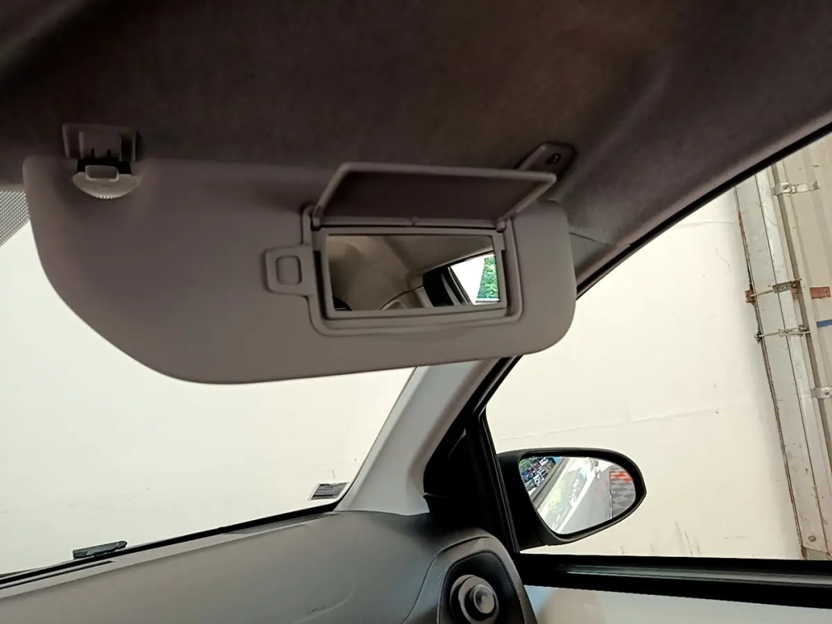 Détail de l'intérieur côté conducteur avec pare-soleil rabattu et miroir de courtoisie ouvert sur Citroën C1 blanc.