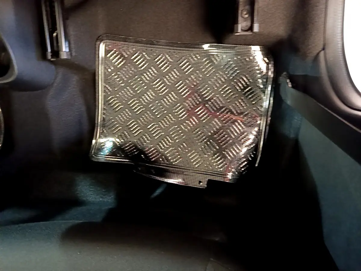 Gros plan sur le tapis de sol en caoutchouc noir à motif damier dans l'habitacle d'une Citroën C1 blanche.