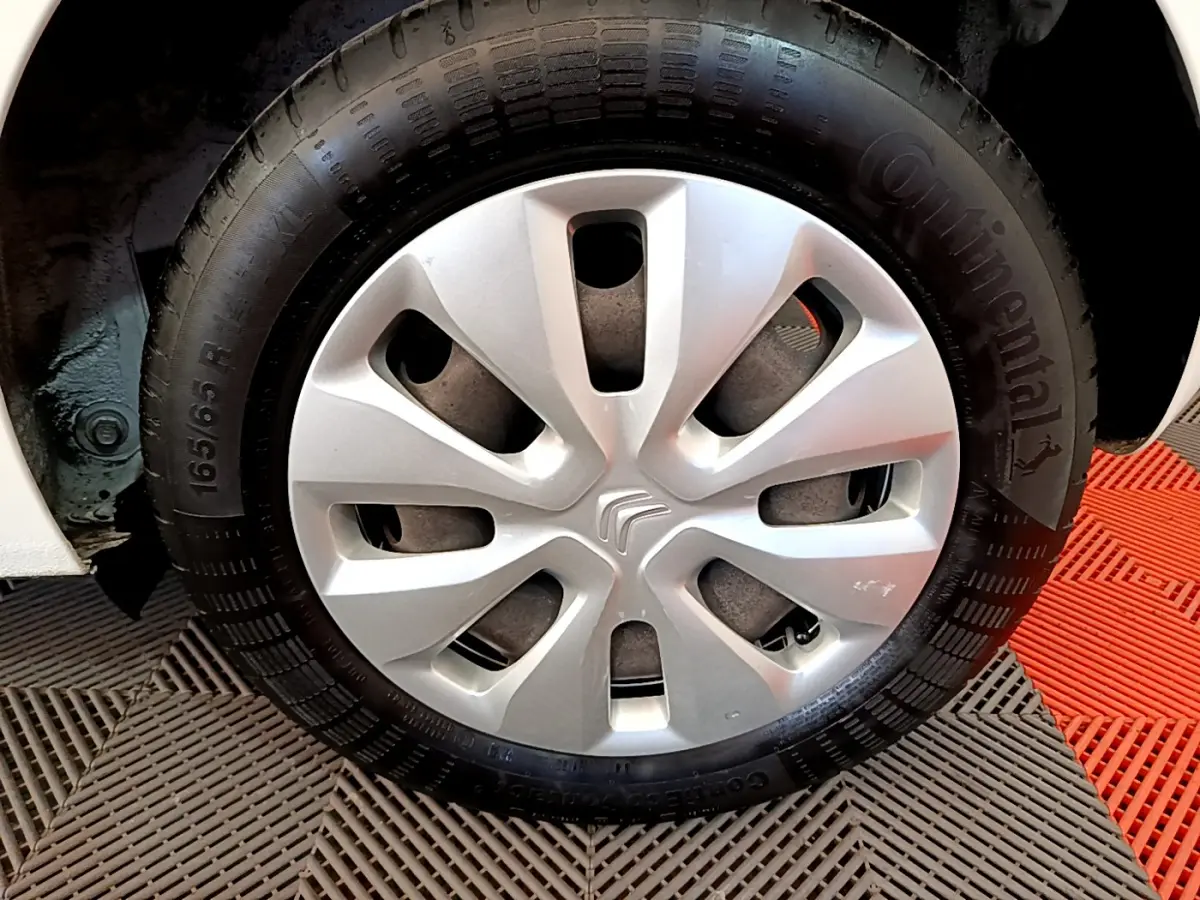Gros plan sur la roue avant droite blanche d'une Citroën C1 2020 avec enjoliveur argenté et pneu Continental.