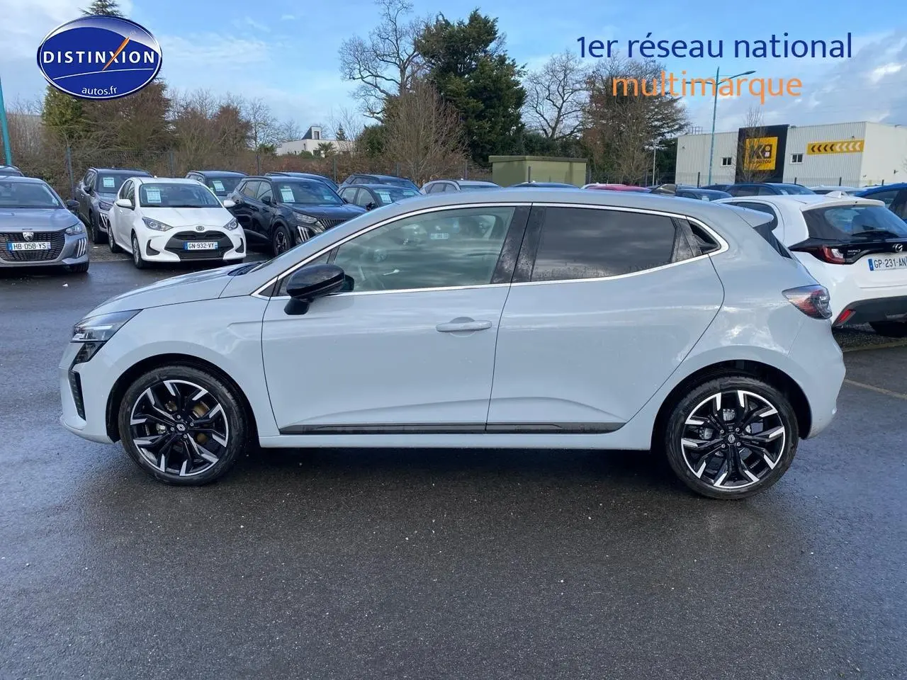 Renault Clio V gris rafale vue de profil côté gauche sur parking avec jantes alliage noires et chromées.