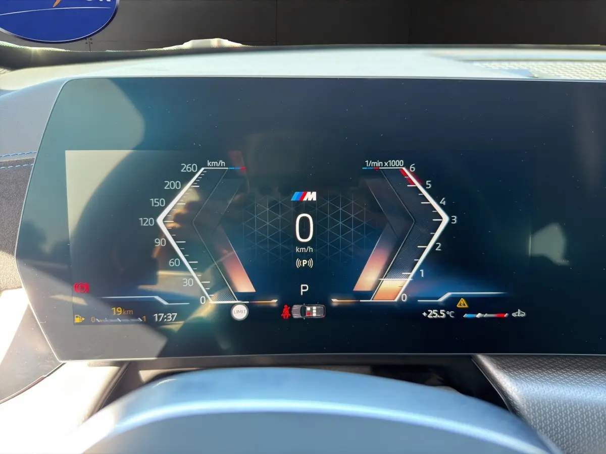 Vue rapprochée du tableau de bord numérique de la BMW X1 sDrive20d blanc, affichant la vitesse et le régime moteur.