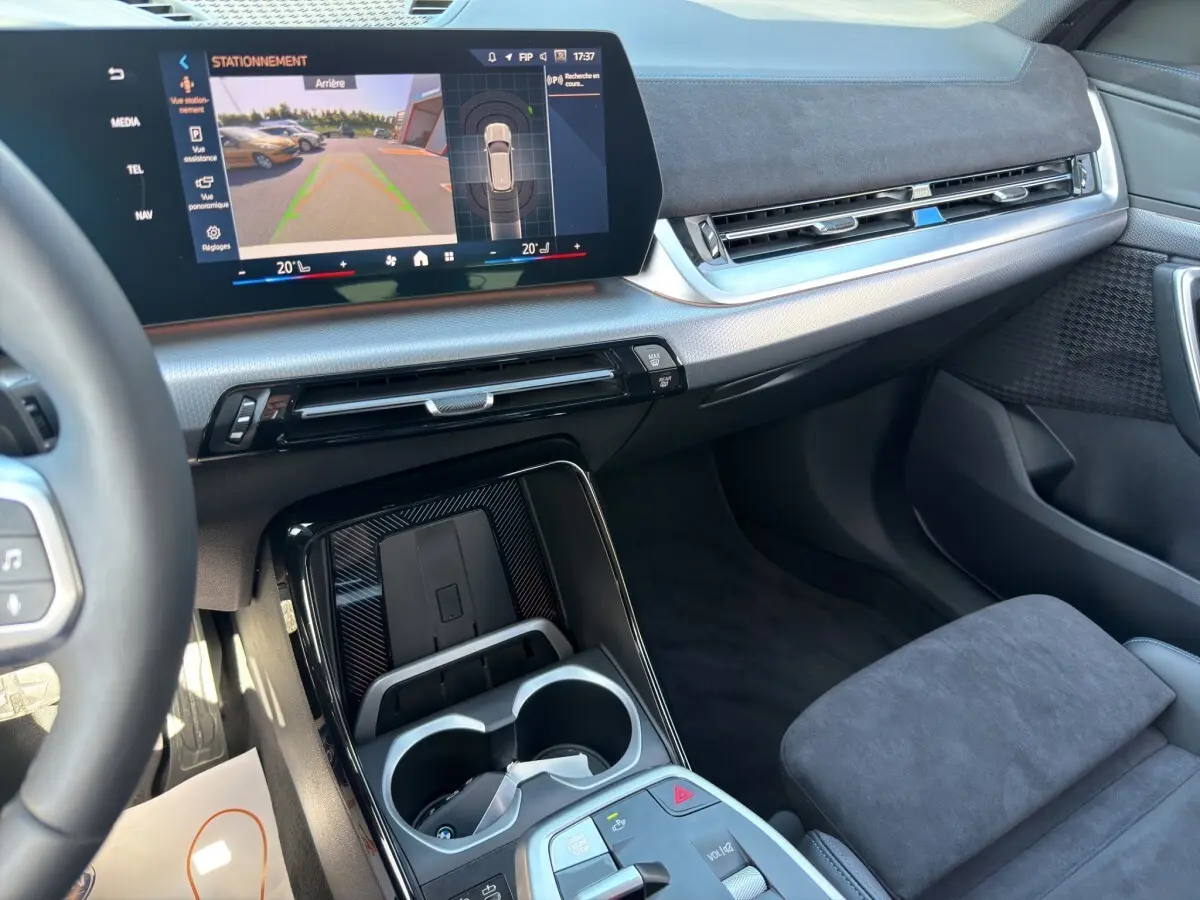 Vue intérieure côté passager du tableau de bord et console centrale noire avec écran tactile du BMW X1 blanc 2025 M SPORT.