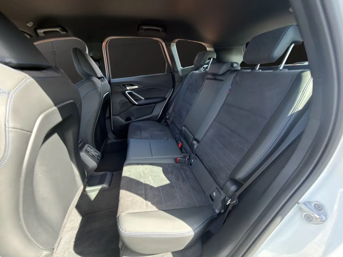 Vue intérieure côté droit des sièges arrière en cuir et alcantara noirs du BMW X1 sDrive20d blanc 2025.
