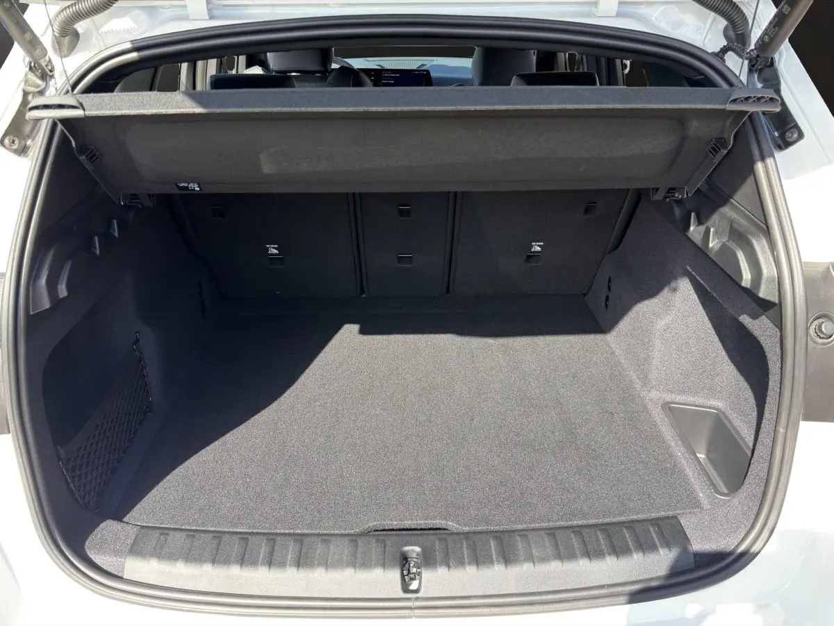 Coffre ouvert vu de l'arrière d'un BMW X1 blanc 2025, espace de chargement propre et spacieux avec cache-bagages.