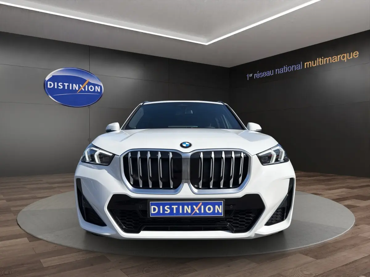 BMW X1 sDrive20d blanc vue de face avec calandre imposante et phares LED dans un showroom