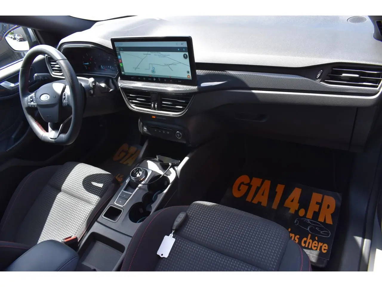 Vue intérieure côté conducteur de la Ford Focus SW 2025, montrant tableau de bord noir et écran tactile central.