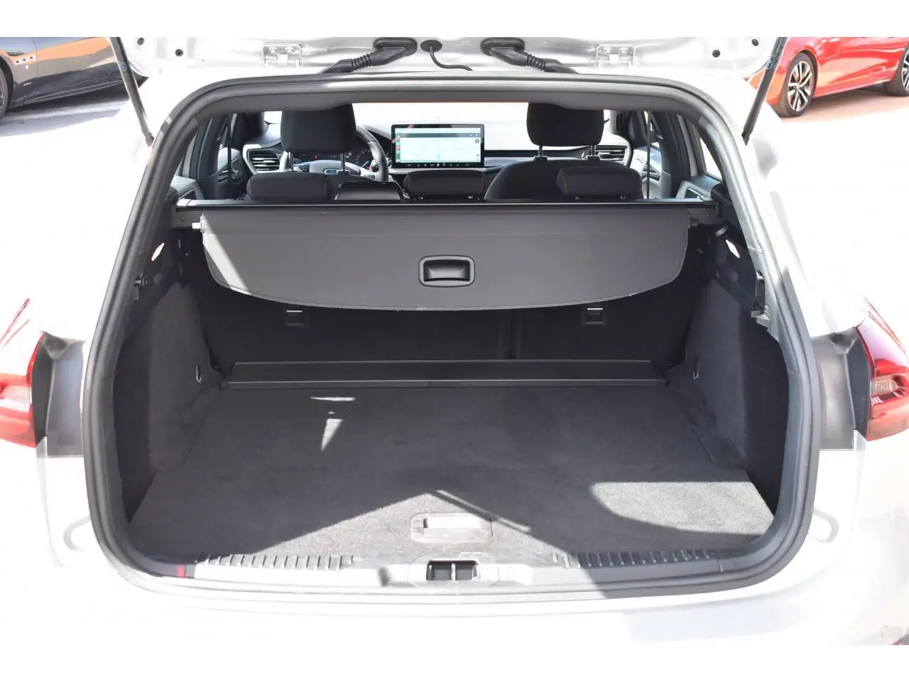 Vue arrière du coffre ouvert d'une Ford Focus SW 1.5 EcoBlue 115 Powershift ST LINE X Moondust Silver, montrant l'espace de chargement et la tablette cache-bagages.