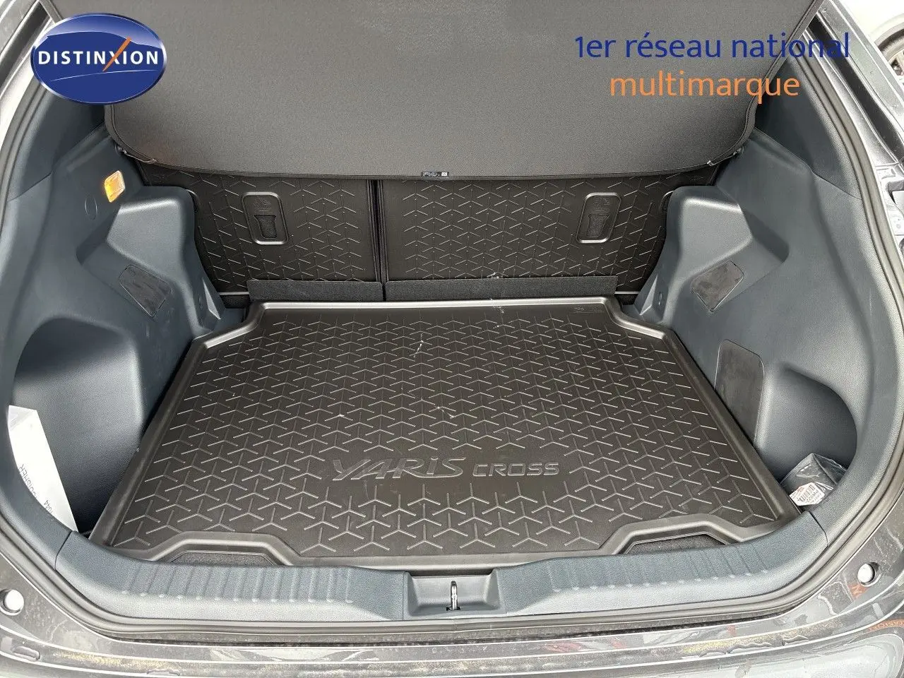 Coffre ouvert de la Toyota Yaris Cross gris atlas metal, vue de l'arrière montrant le tapis de coffre avec logo Yaris Cross.