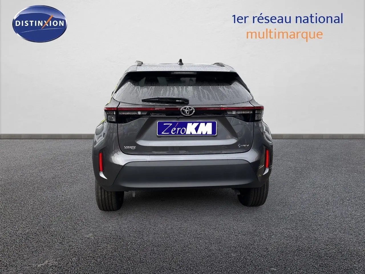 Vue arrière d'une Toyota Yaris Cross gris atlas métal avec feux arrière LED et logo hybride visible.