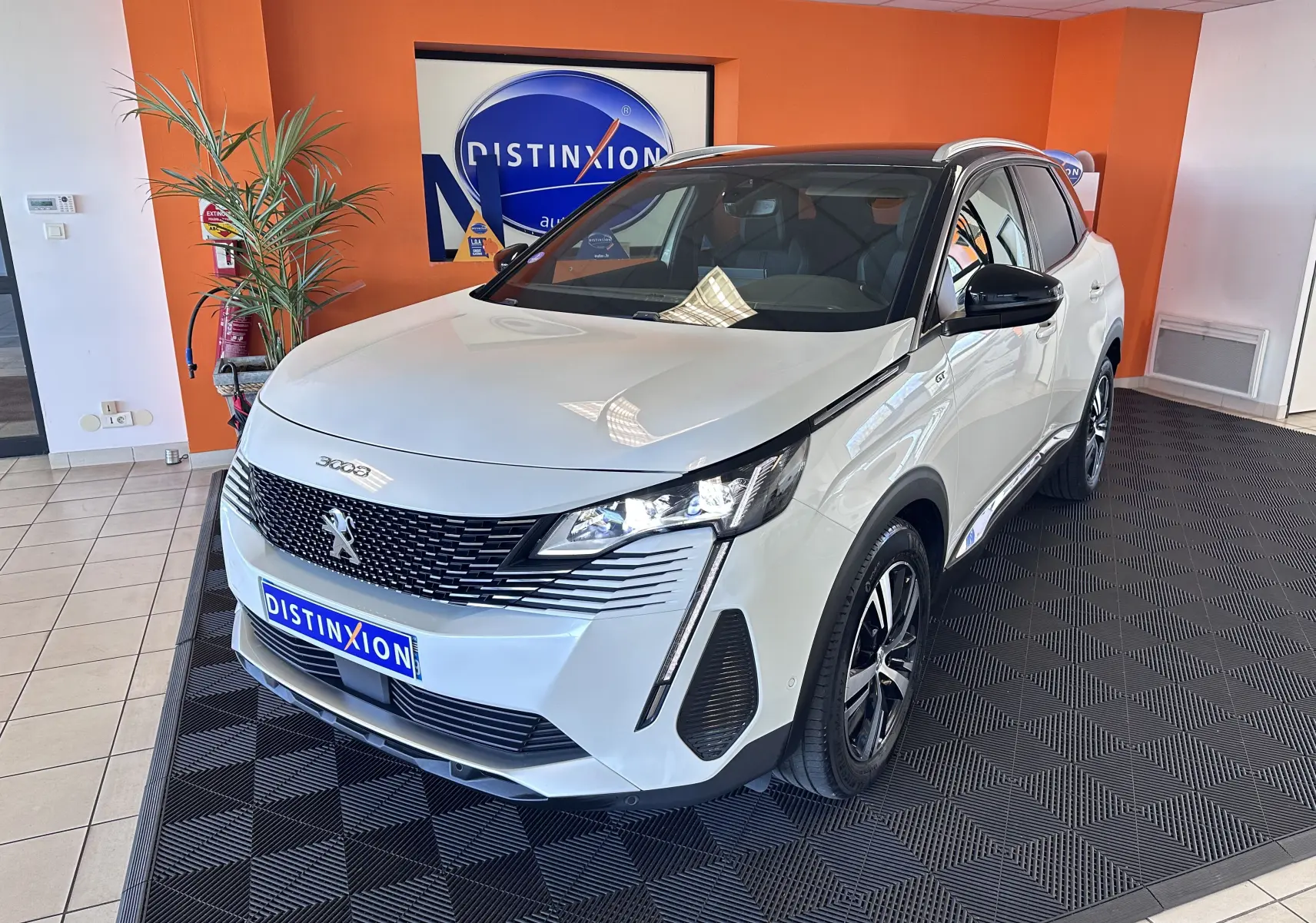 Peugeot 3008 blanc nacré en 3/4 avant droit, avec toit noir et jantes alliage distinctives, en intérieur showroom.