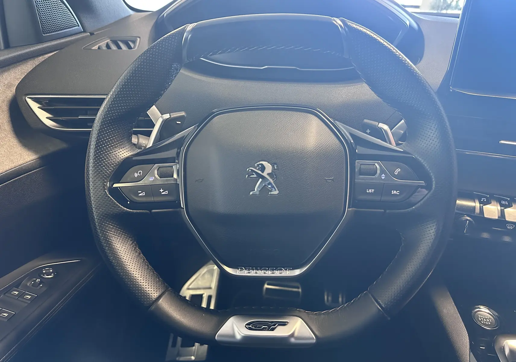 Vue rapprochée du volant cuir noir avec logo Peugeot et badge GT du Peugeot 3008 blanc nacré 2022.