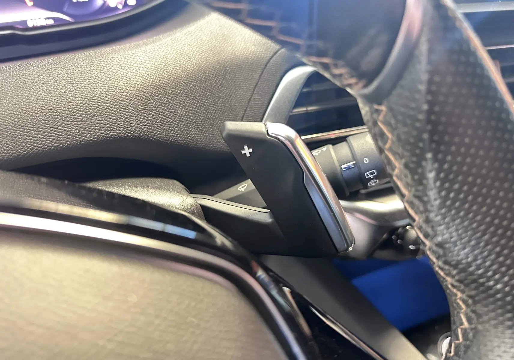 Gros plan sur la palette de changement de vitesse droite en plastique noir et chrome, volant cuir perforé Peugeot 3008 blanc nacré.