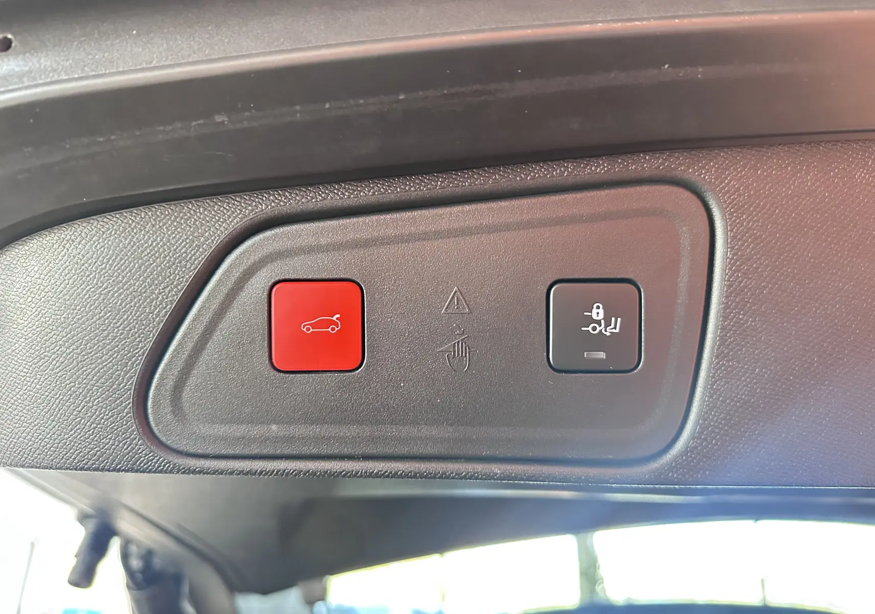 Gros plan sur les boutons de commande du hayon électrique et du verrouillage des sièges arrière, intérieur noir du Peugeot 3008 blanc nacré.