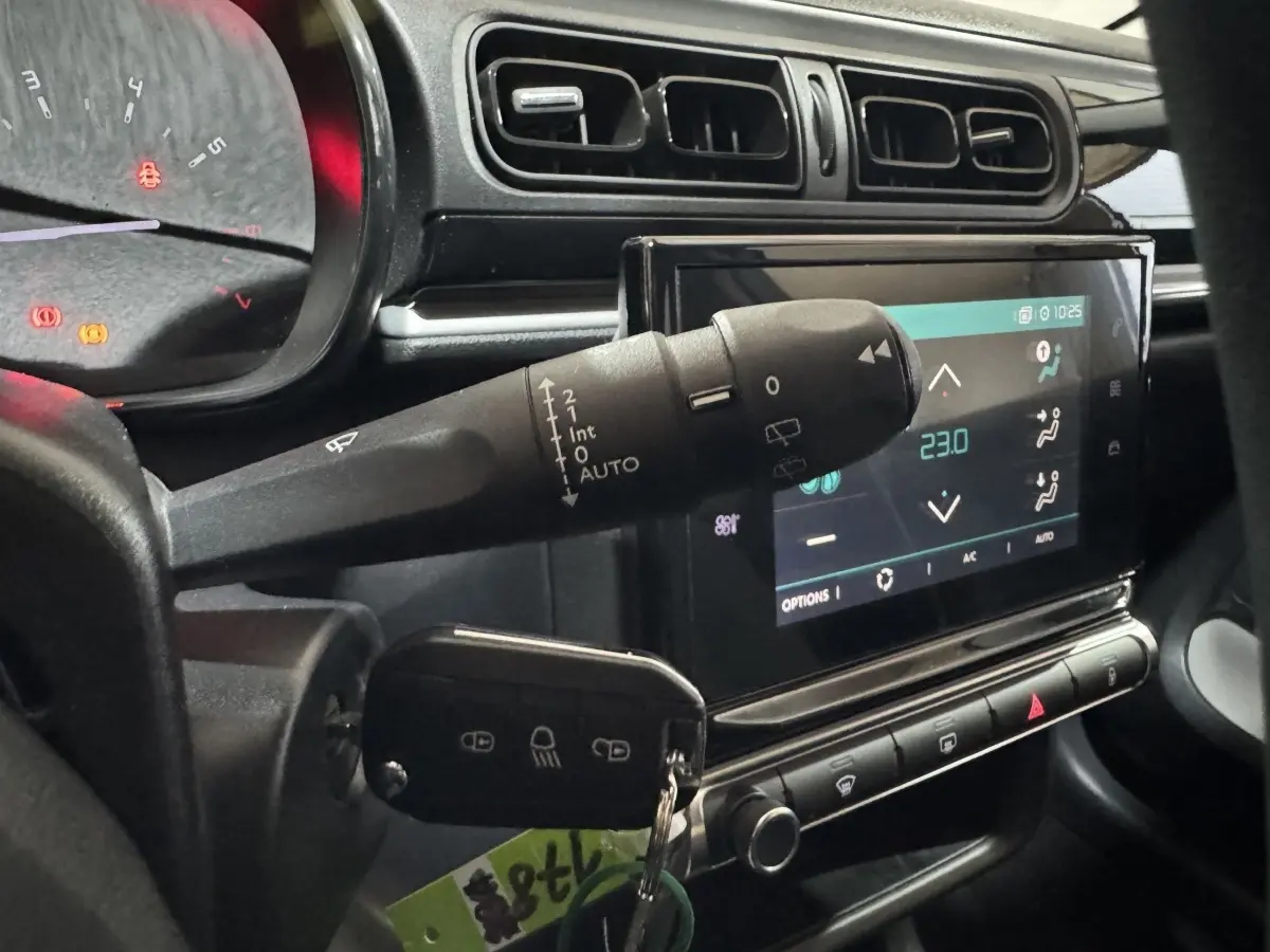 Vue rapprochée de l'intérieur de la Citroën C3 bleu, montrant le commodo d'essuie-glace et l'écran tactile central.