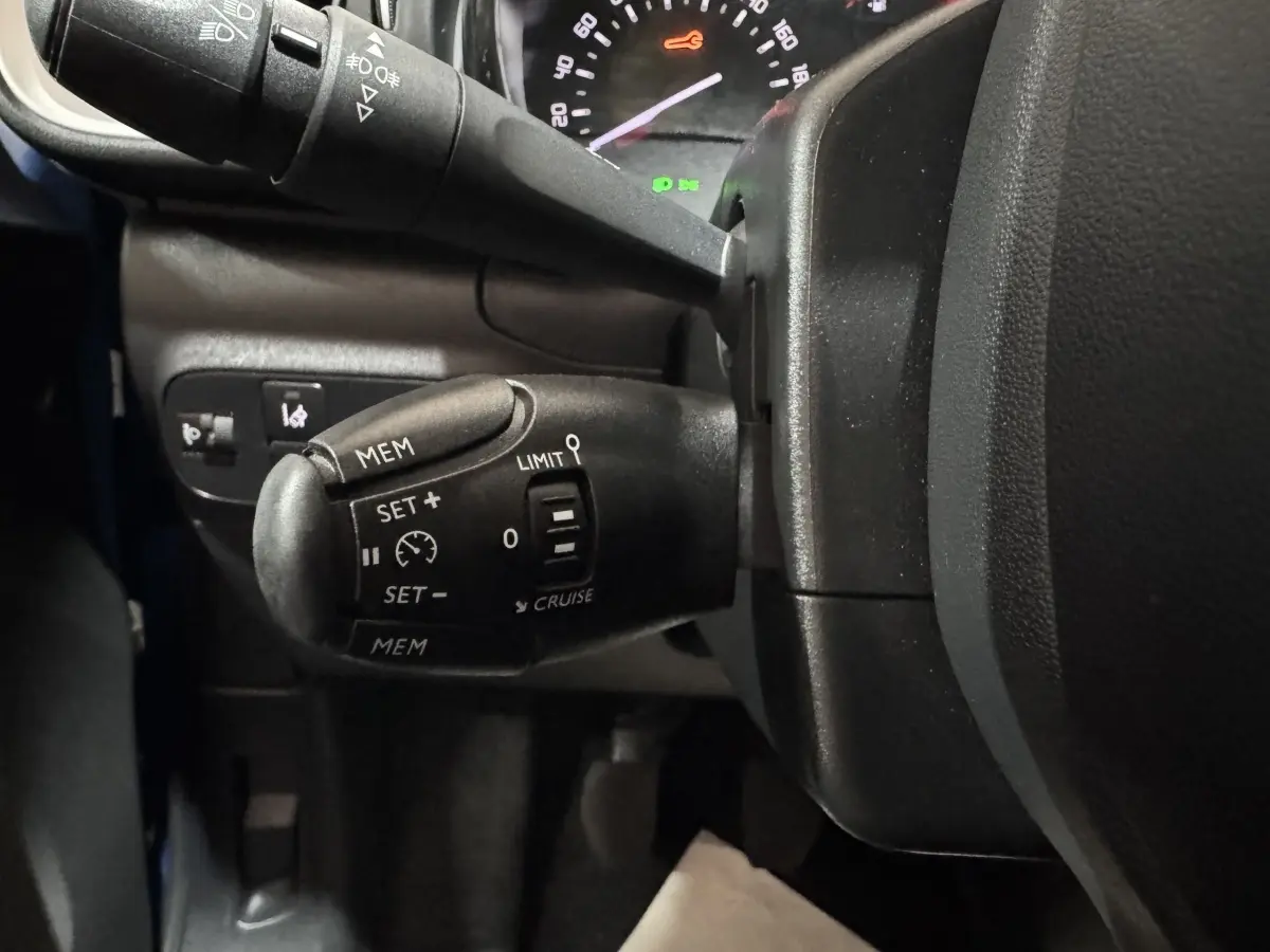 Gros plan sur la commande de régulateur de vitesse à gauche du volant dans l’habitacle d’une Citroën C3 bleu 2018.