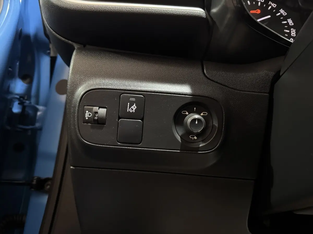 Détail des commandes côté gauche du tableau de bord d’une Citroën C3 bleu 2018, avec réglage des phares et rétroviseurs.