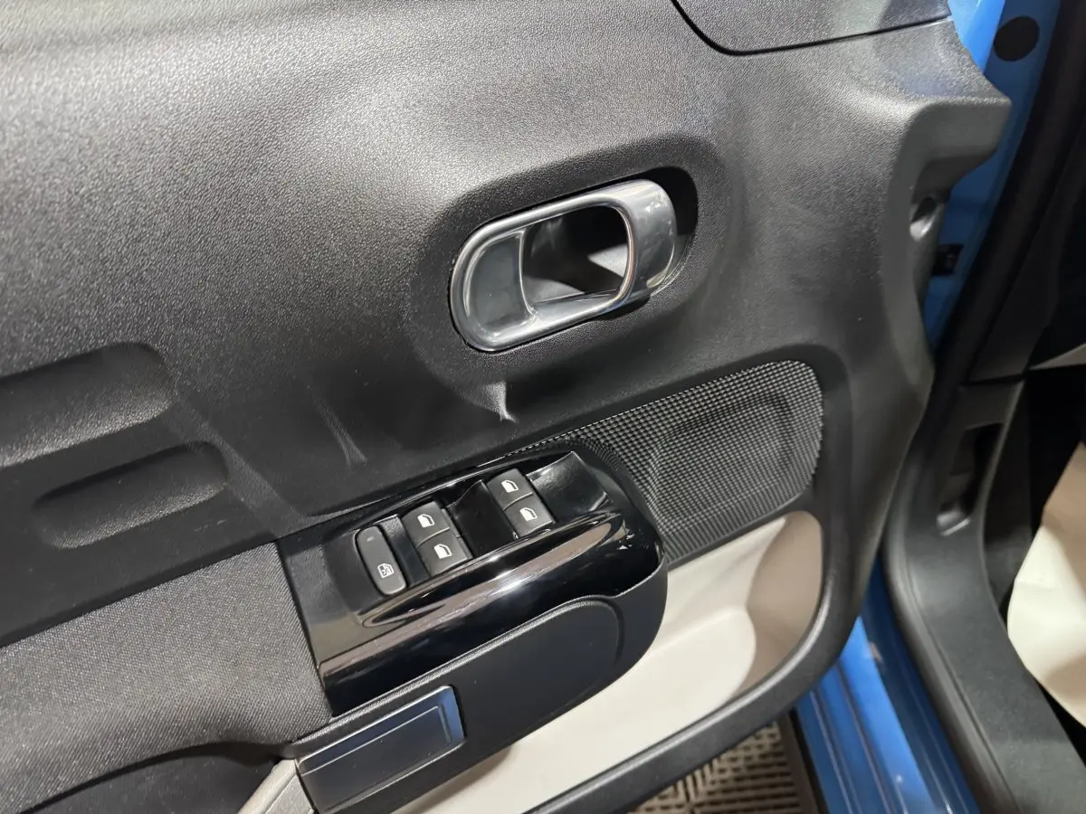 Gros plan sur la porte avant gauche bleu de la Citroën C3 2018, avec commandes de vitres et poignée intérieure chromée.