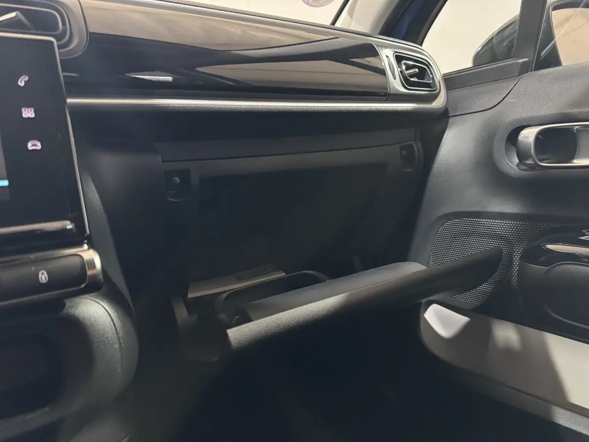 Intérieur de la Citroën C3 bleu, vue sur la boîte à gants ouverte côté passager avec tableau de bord noir.