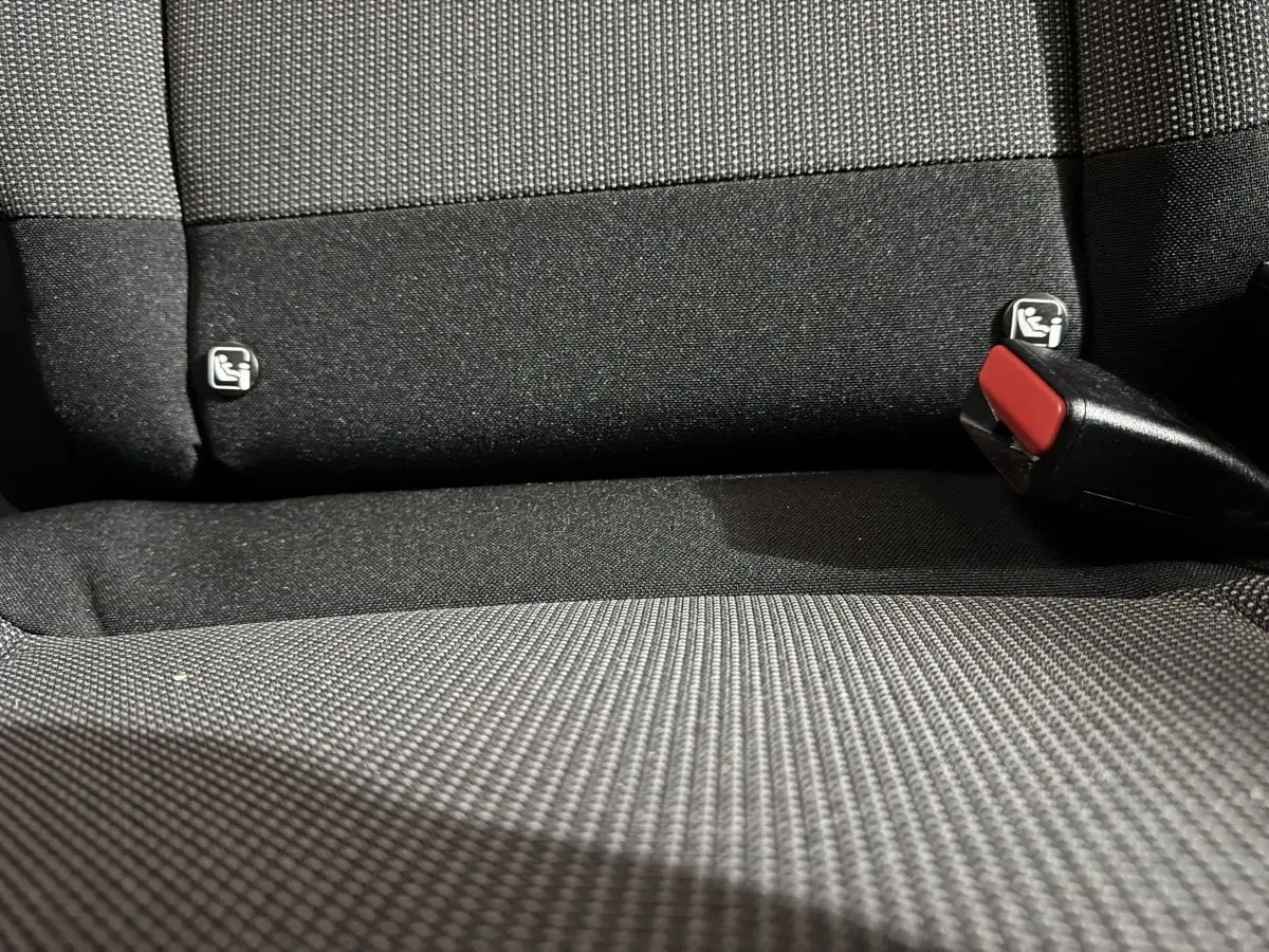 Gros plan sur la banquette arrière noire de la Citroën C3 avec fixation Isofix et boucle de ceinture rouge visible.