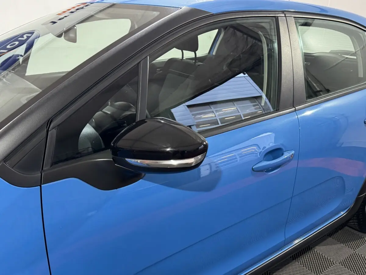 Vue latérale côté gauche d'une Citroën C3 bleu avec rétroviseur noir brillant et poignée de porte visible.