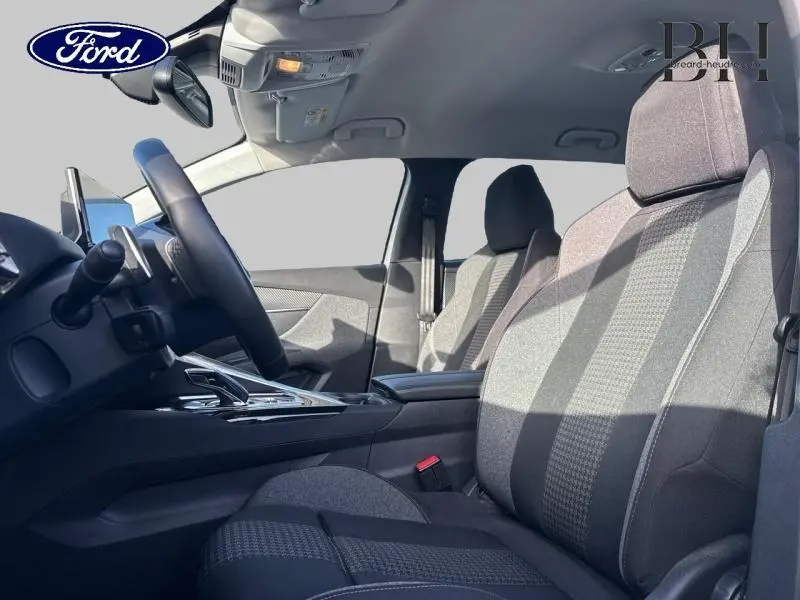 Vue intérieure côté conducteur du Ford montrant le volant, les sièges en tissu gris et la console centrale.