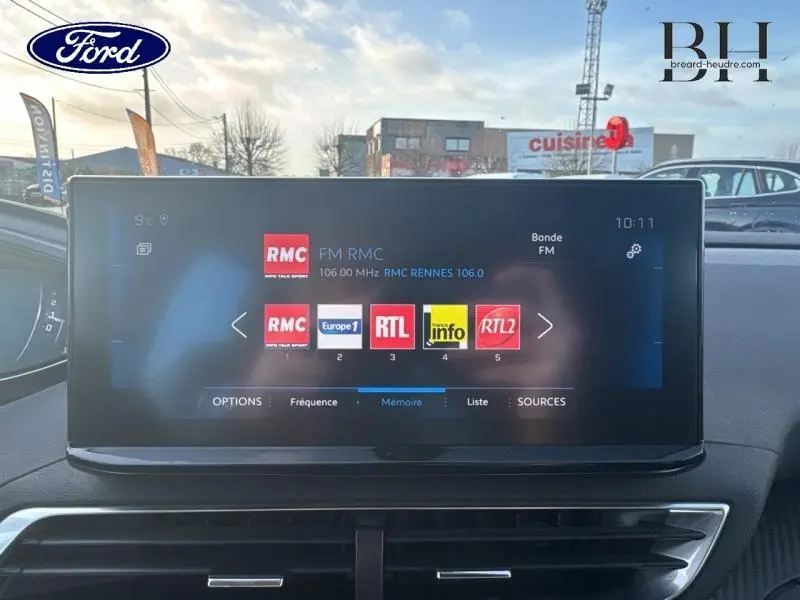 Peugeot 5008 blanc Banquise vue de face en intérieur, écran tactile multimédia allumé sur radio FM.