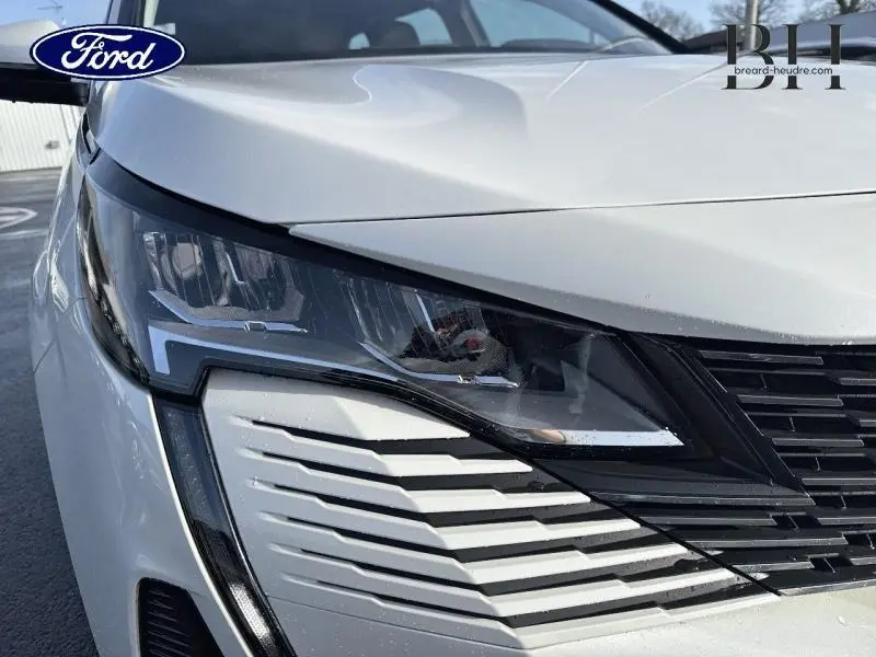 Gros plan sur le phare avant gauche blanc Banquise du Peugeot 5008 avec calandre noire et détails anguleux.