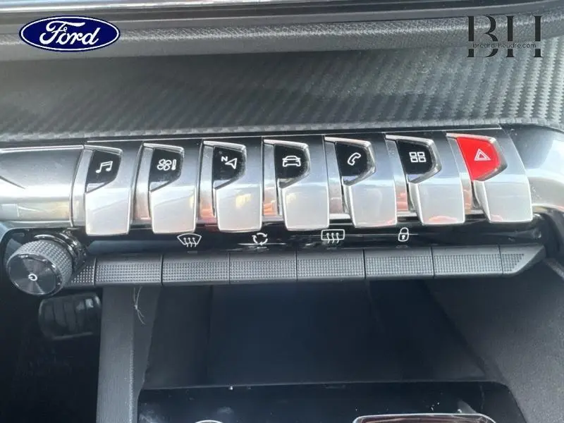 Gros plan sur les commandes chromées du tableau de bord du Peugeot 5008 blanc Banquise, avec inserts carbone.
