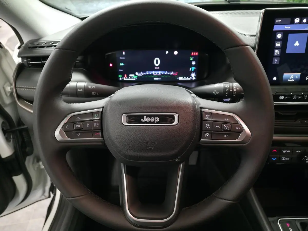 Vue rapprochée du volant Jeep Compass 2024 noir avec tableau de bord numérique et écran tactile central visible.