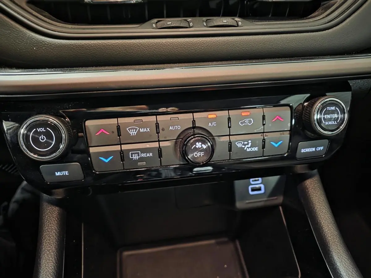 Gros plan sur la console centrale noire du Jeep Compass 2024, montrant les commandes de climatisation et audio.