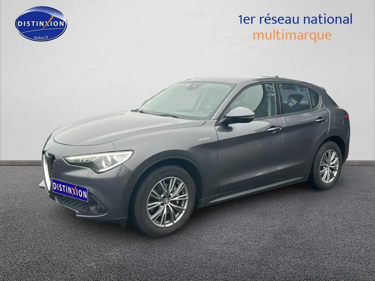 Vue 3/4 avant droit d'une Alfa Romeo Stelvio gris vesuvio metal avec jantes alu et feux LED.
