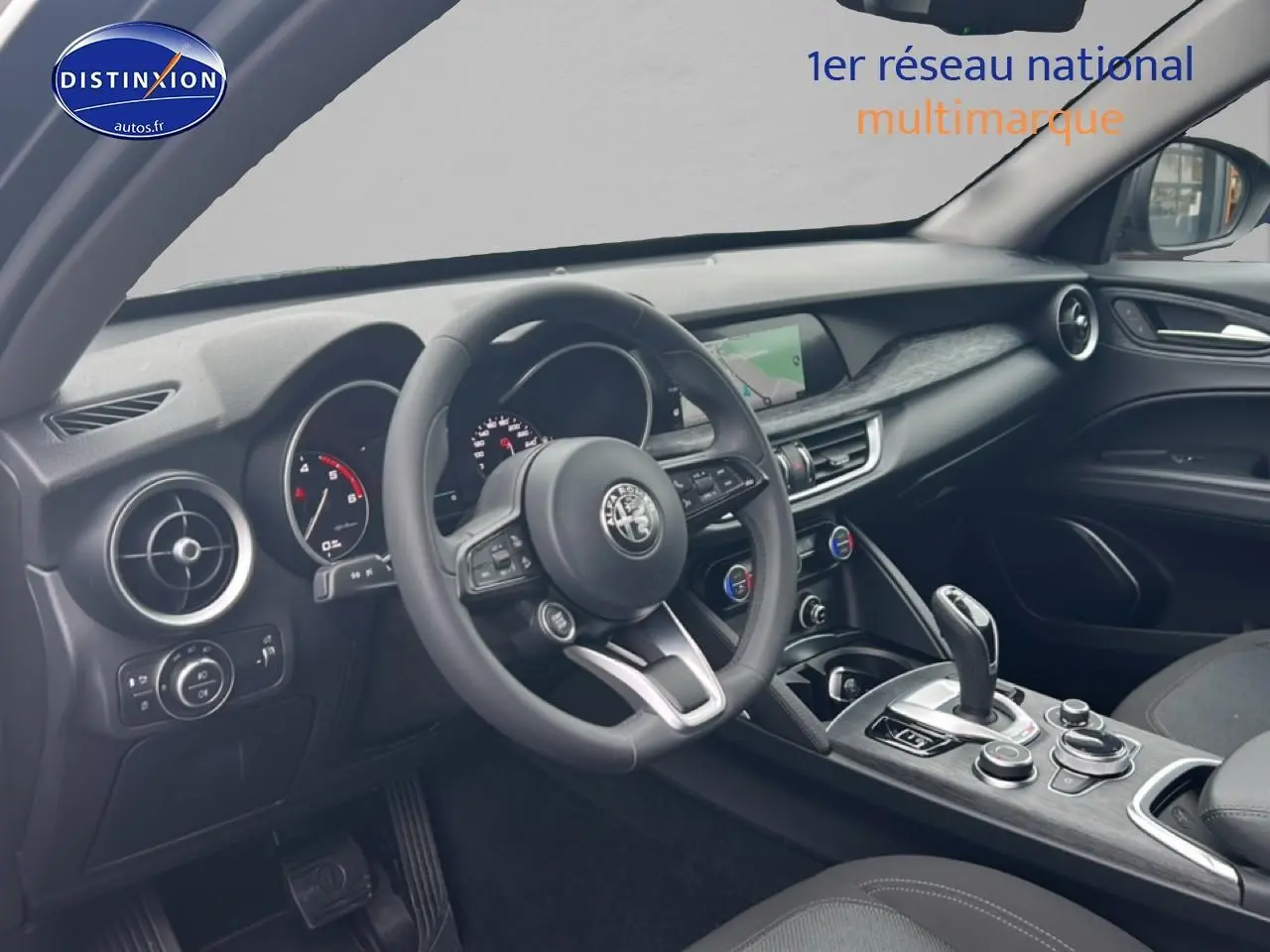 Vue intérieure côté conducteur de l'Alfa Romeo Stelvio gris Vesuvio, volant cuir multifonction et écran tactile central.