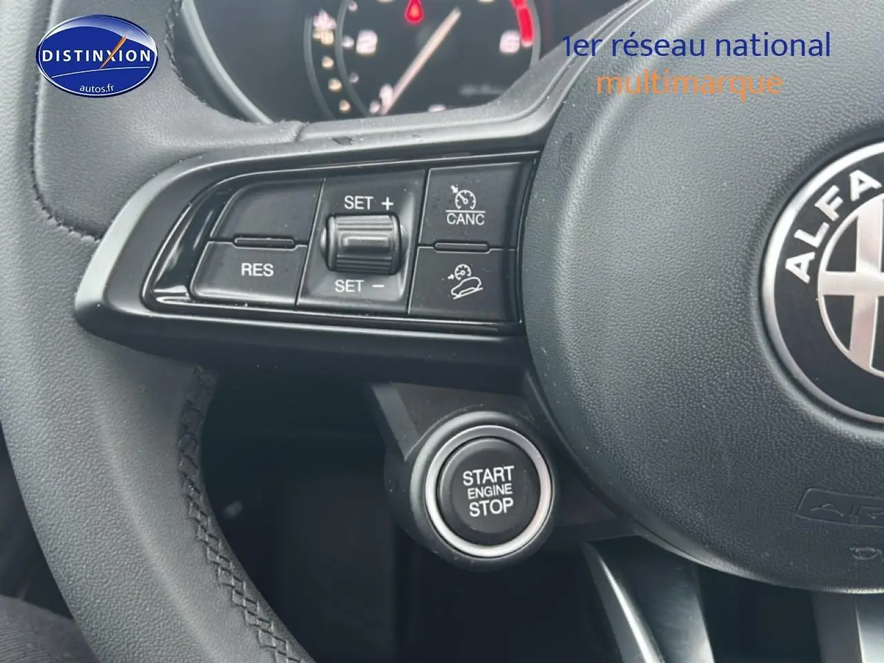 Gros plan sur le volant cuir noir d'Alfa Romeo Stelvio avec commandes de régulateur et bouton start/stop visible.