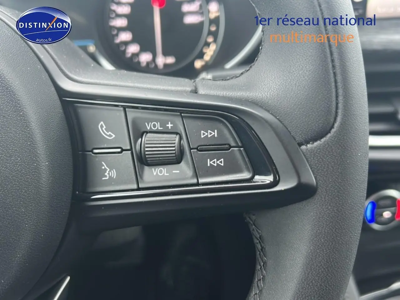 Gros plan sur les commandes audio au volant cuir noir de l'Alfa Romeo Stelvio gris Vesuvio metal, intérieur moderne.