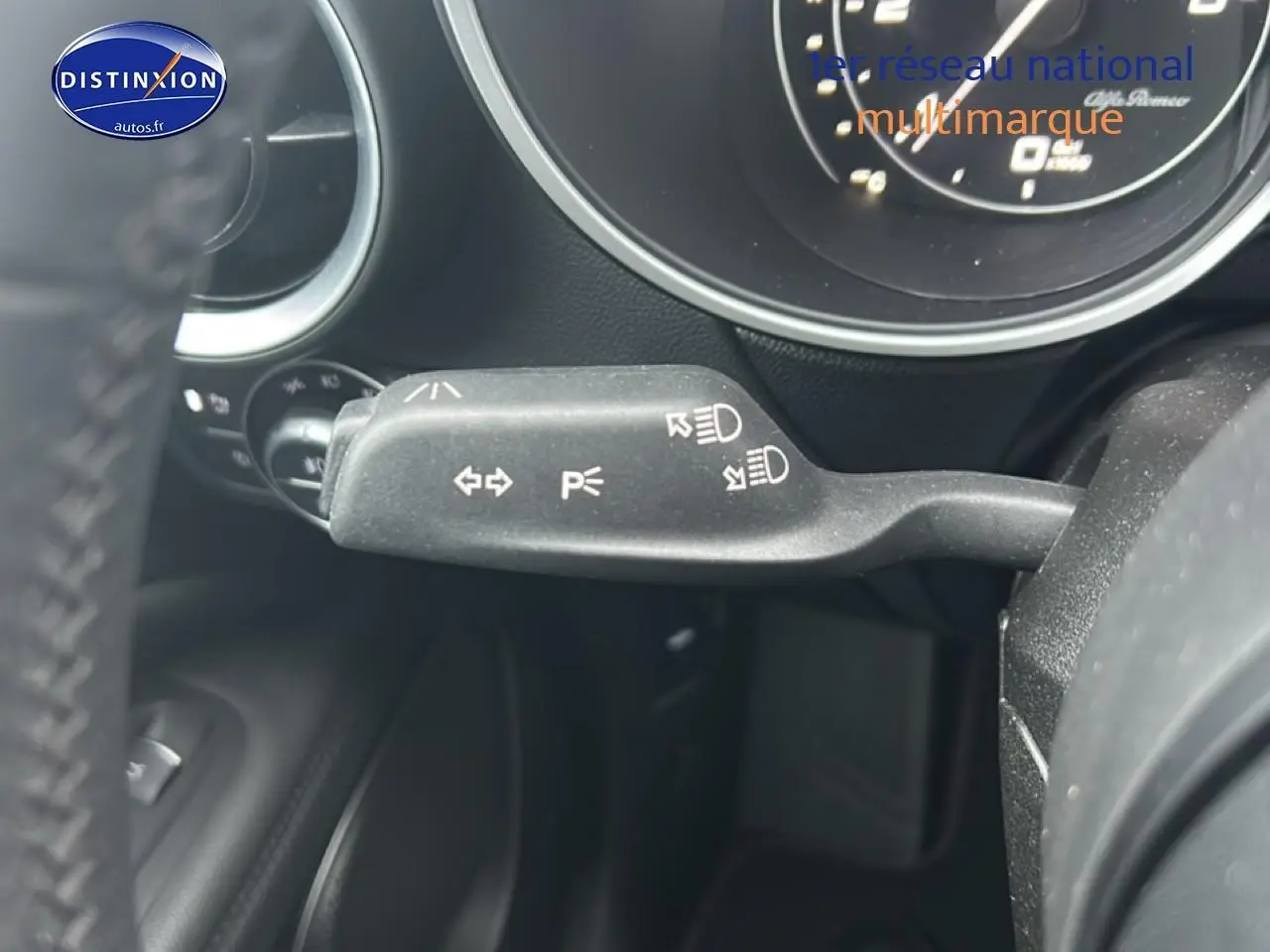 Gros plan sur la commande de clignotants et feux à gauche du volant d'Alfa Romeo Stelvio gris Vesuvio metal.