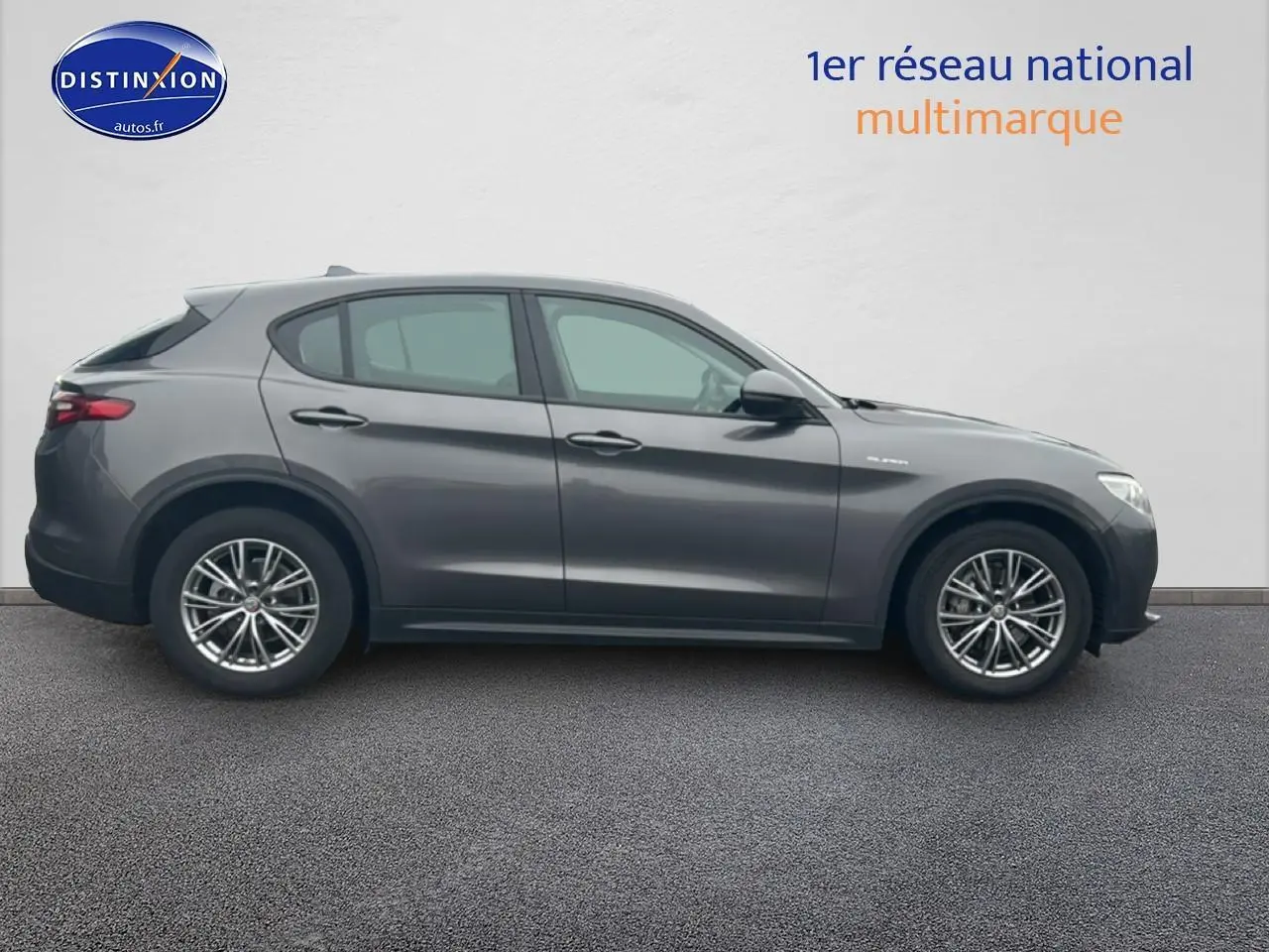 Vue de profil côté gauche d'un Alfa Romeo Stelvio gris vesuvio metal avec jantes alu multibranches.