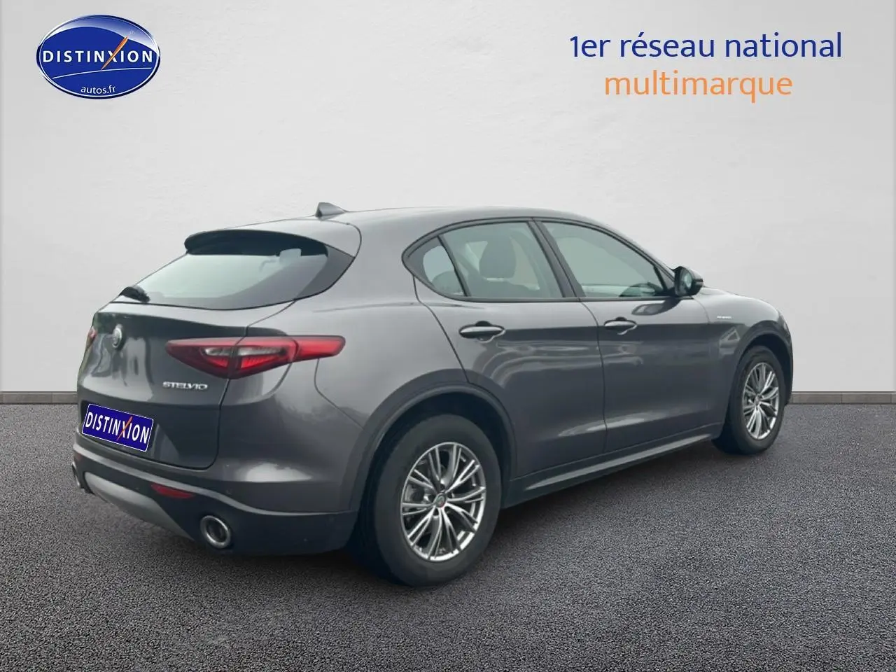Vue 3/4 arrière droite d'un Alfa Romeo Stelvio gris Vesuvio metal avec jantes alu et feux arrière LED.