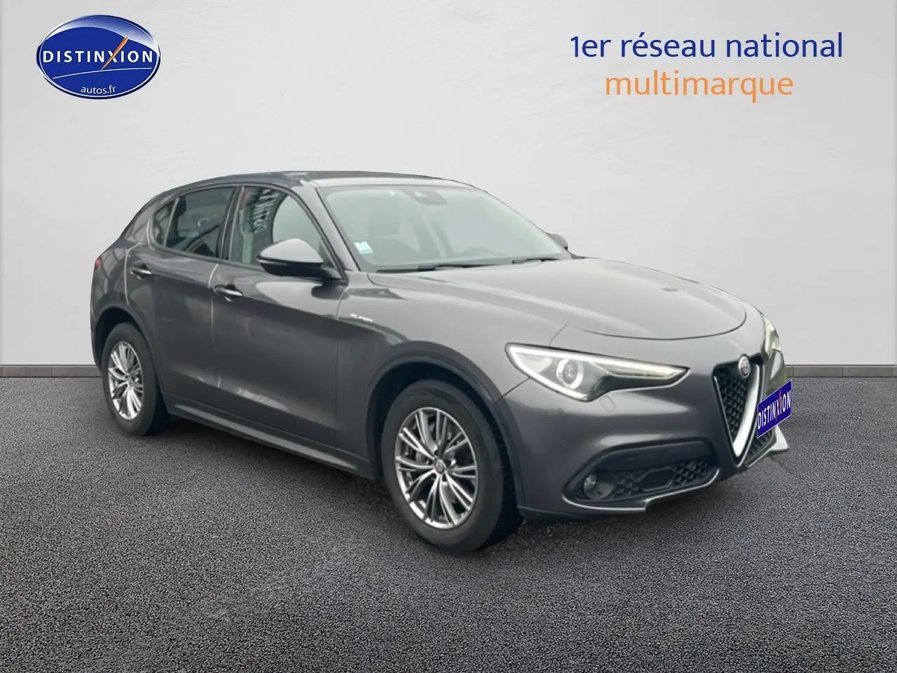 Alfa Romeo Stelvio gris Vesuvio métal en 3/4 avant droit, avec calandre caractéristique et jantes alu multibranches.