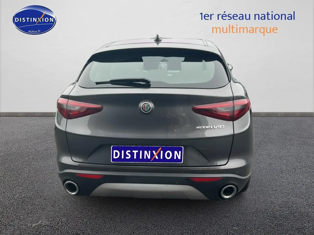 Vue arrière d'un Alfa Romeo Stelvio gris vesuvio metal avec double sortie d'échappement et feux arrière LED.