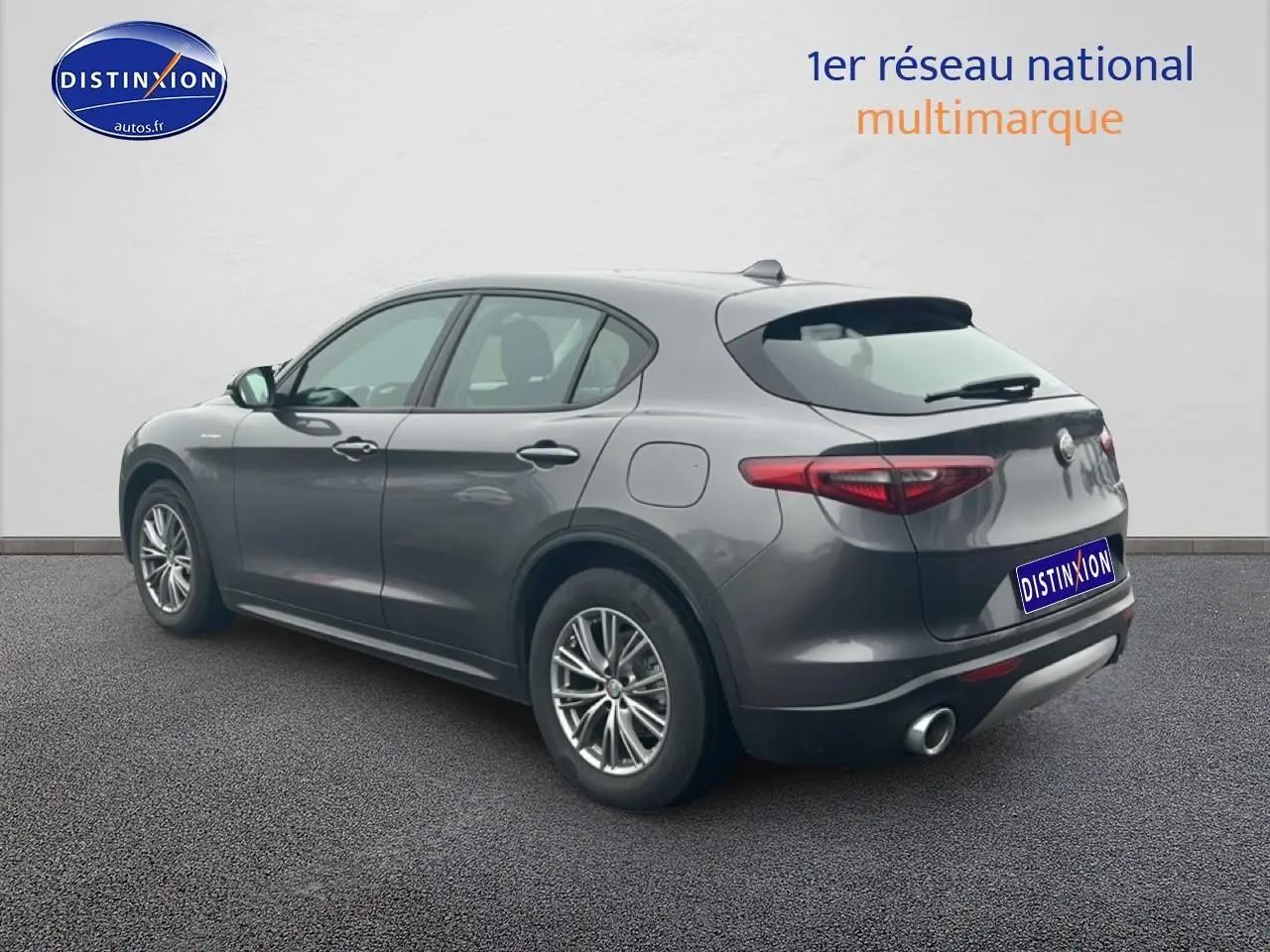 Vue 3/4 arrière droite d'un Alfa Romeo Stelvio gris Vesuvio metal avec échappement double et jantes alu.