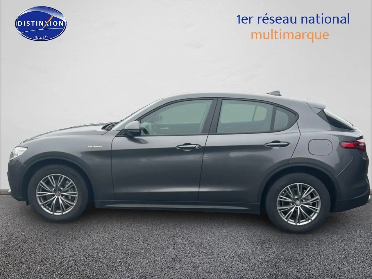 Profil droit d'un Alfa Romeo Stelvio gris vesuvio metal, mettant en valeur ses jantes alliage et lignes fluides.