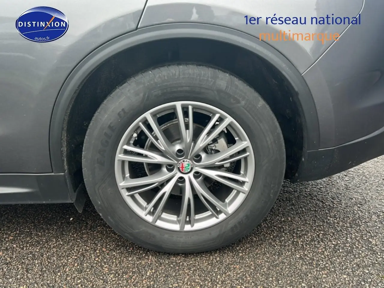 Gros plan sur la roue arrière droite avec jante alu argentée de l'Alfa Romeo Stelvio gris Vesuvio metal.