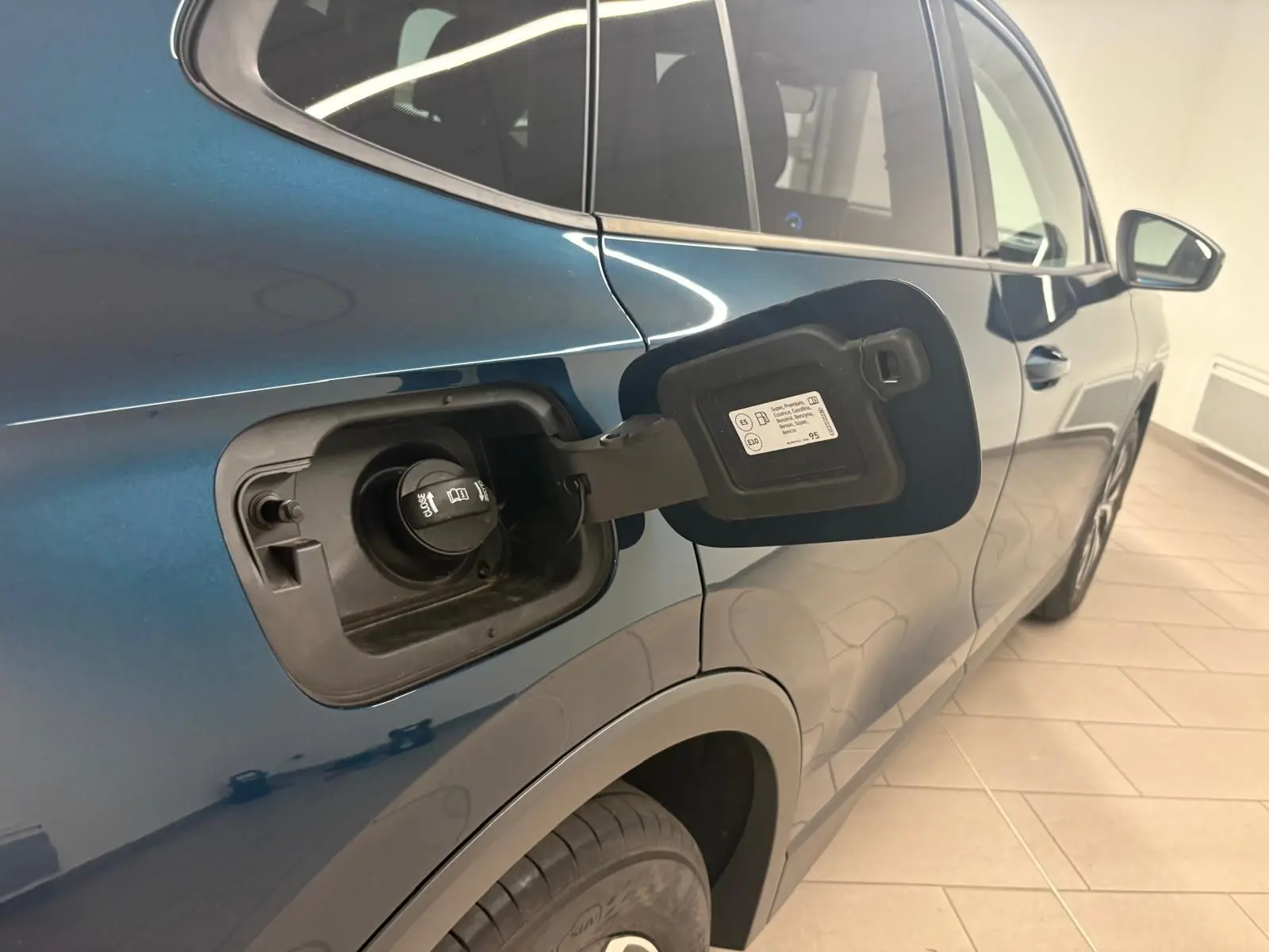 Vue côté gauche arrière du Volkswagen Tiguan 1.5 eHybrid en bleu Nightshade, trappe de recharge ouverte visible.